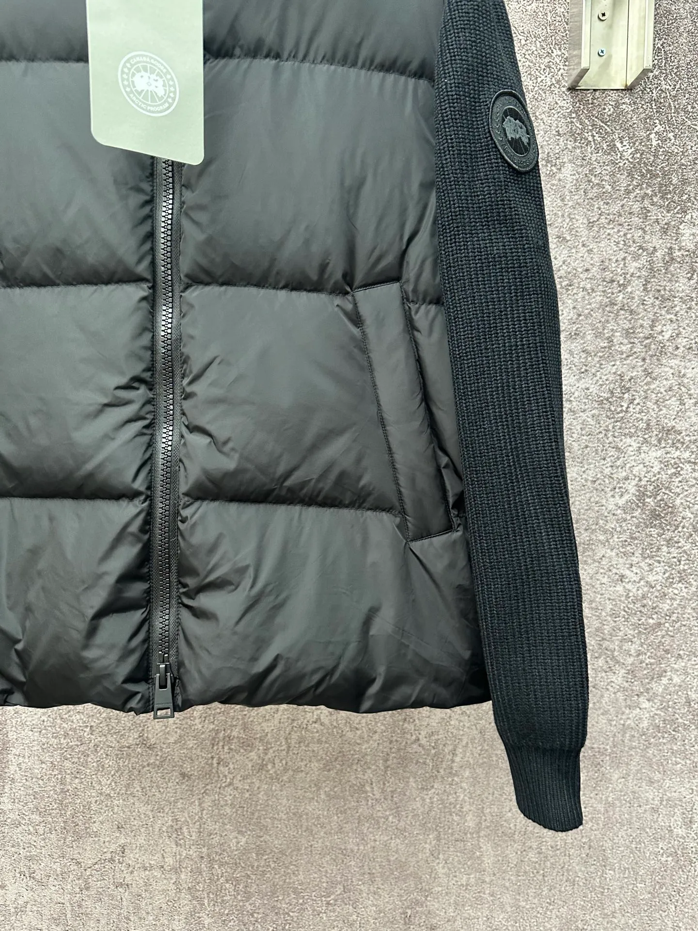 P930 Canada Goose Armband Hooded Down Jacket Fabric selection: The use of high-quality protective nylon fabric not only enhances the wear resistance of the surface, but also takes into account wind resistance, ensuring excellent performance in various harsh weather conditions.  90 national standard high-quality white duck down: selected high-loft down, weighing 170g, light and warm, with excellent temperature locking performance and good resilience.  Three-dimensional quilting process: Precision thread reinforcement to prevent velvet drilling and ensure that the fluffy and resilient elasticity lasts as new.  7-needle medium-thick knitted structure: Use thicker yarns to knit woolen fabrics with obvious thickness and weight. The texture is clearly visible and has a rough, retro texture. It has a good skeleton feel, is relatively stiff, and can maintain the silhouette of clothing for a long time. It also provides more layers of still air to lock in heat.  There is a brand exclusive LOGO on the woolen sleeve arms. It is dark and not obvious in the photo.  Accessories: One-to-one customized logo, one-to-one customized zipper pendant, one-to-one customized snap button SIZE: S M L XL